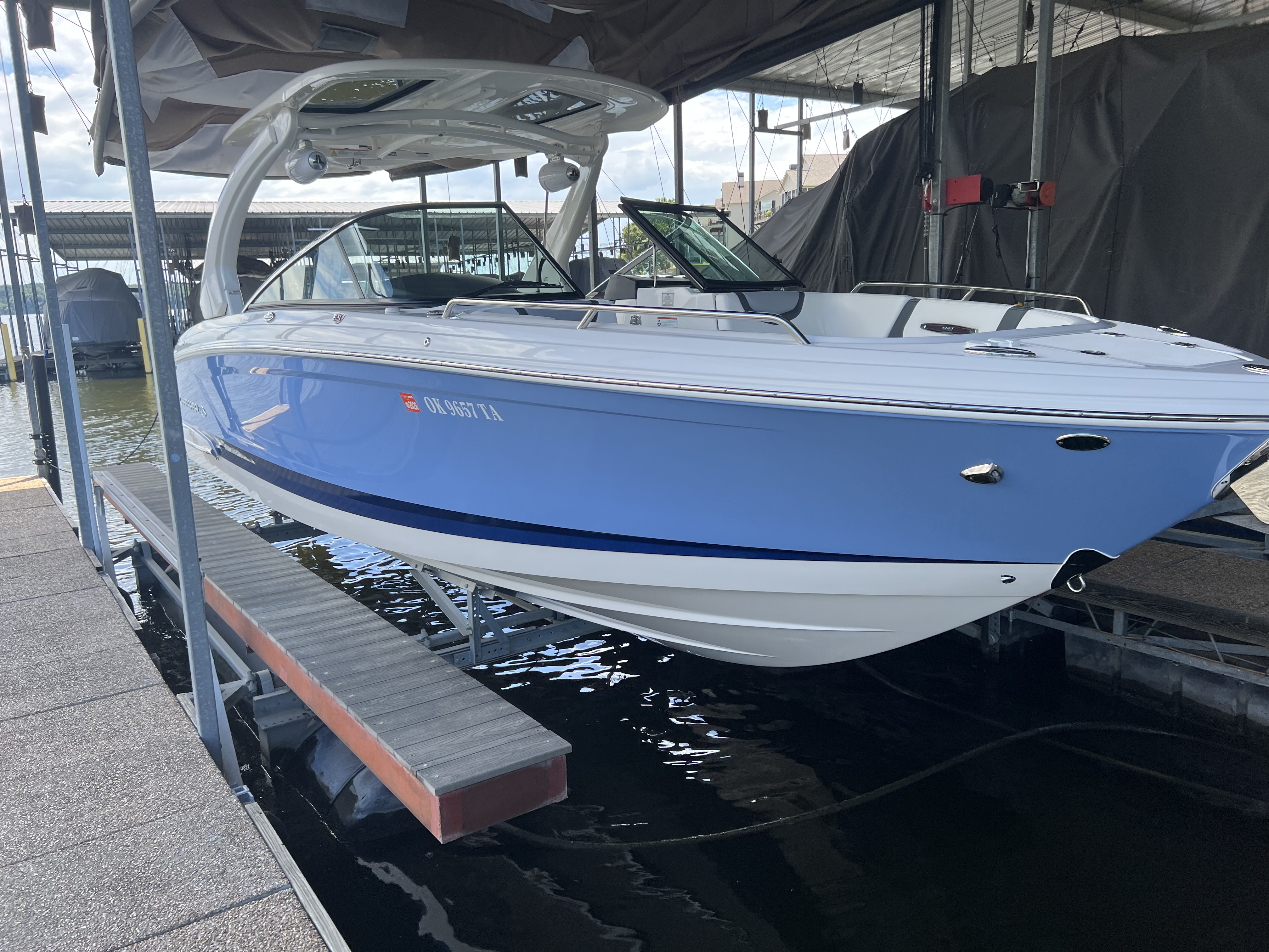Polished light blue and white bowrider on a boat lift under a covered dock