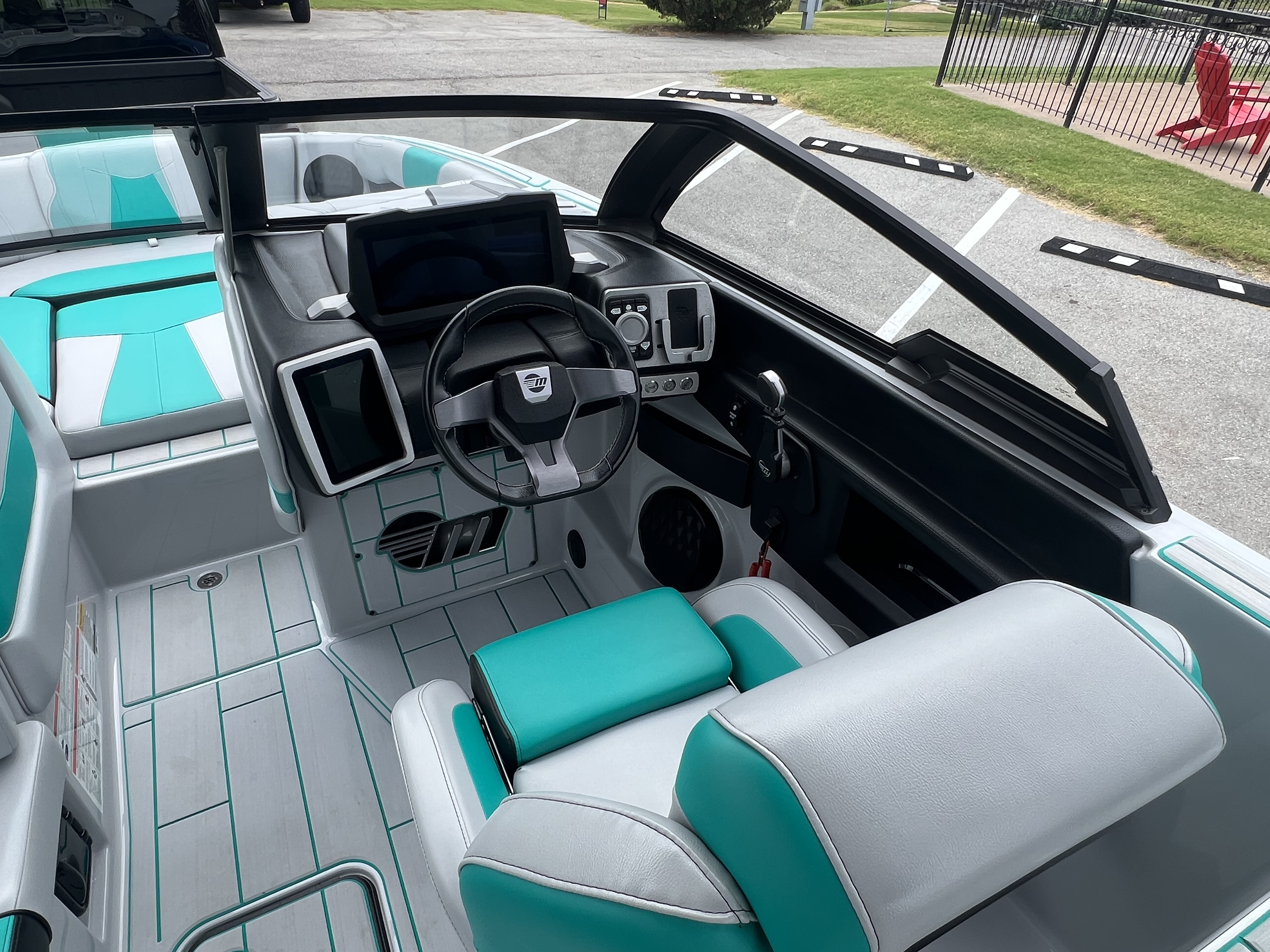 Clean teal and white cockpit interior of the Malibu wake boat with teak-look decking