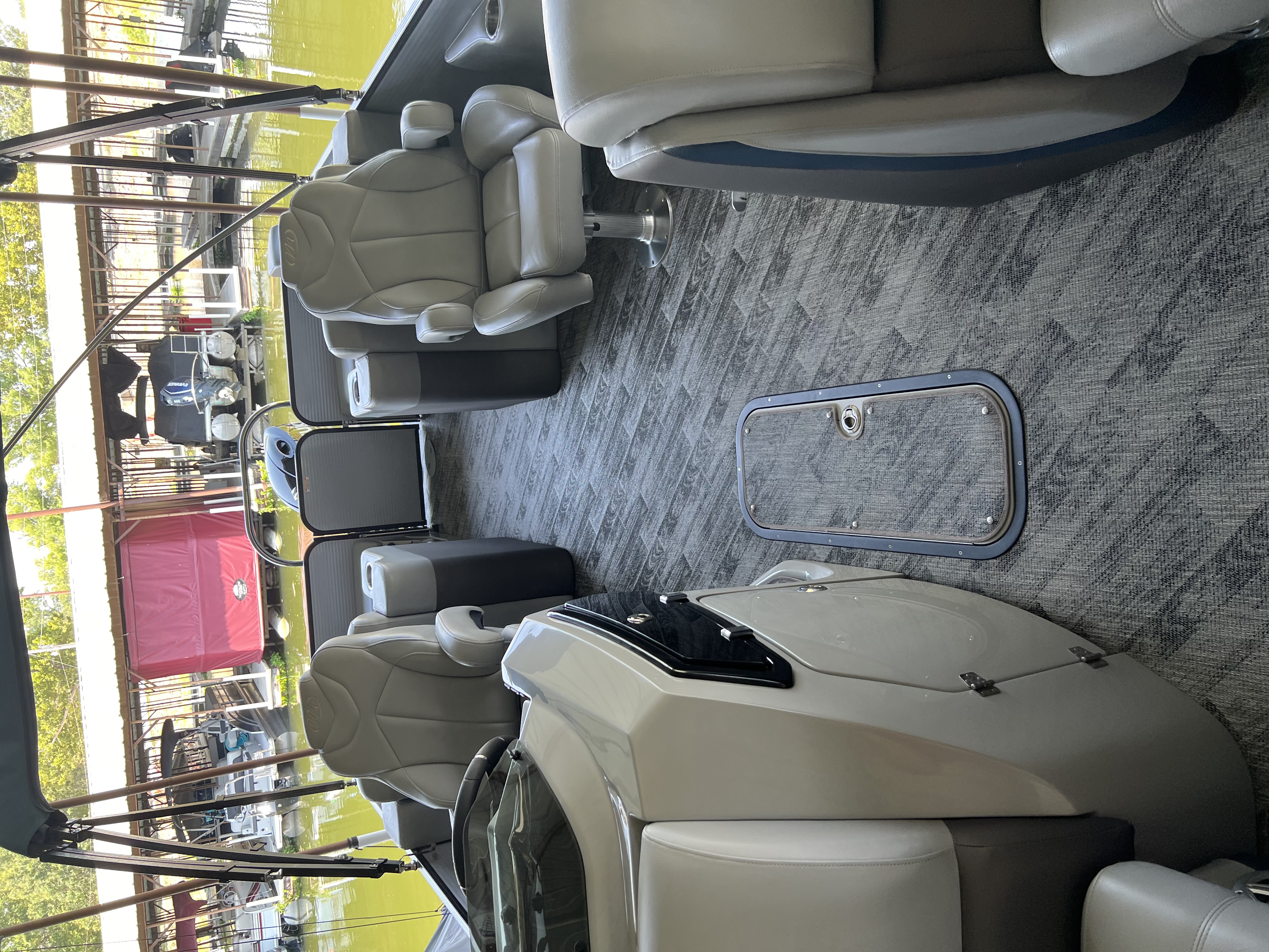 Clean pontoon boat interior with gray captain chairs, helm and patterned carpet